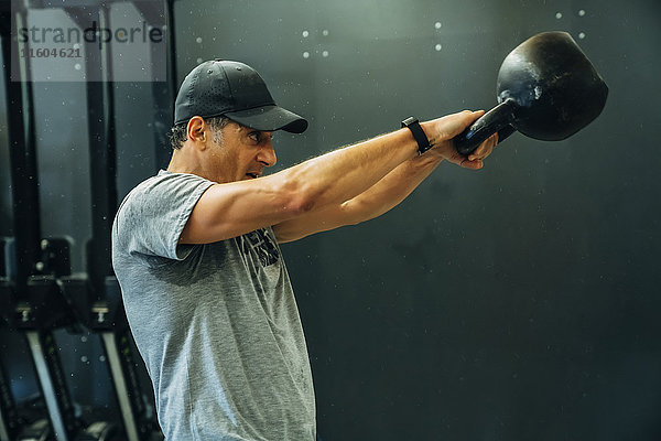 Porträt eines kaukasischen Mannes  der eine Kettlebell hebt