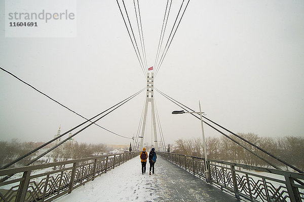 Kaukasische Frauen beim Überqueren einer Brücke im Winter