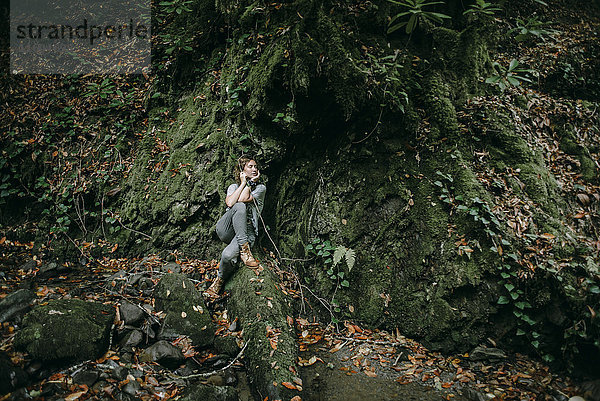 Kaukasische Frau sitzt im Wald und hält einen Ast
