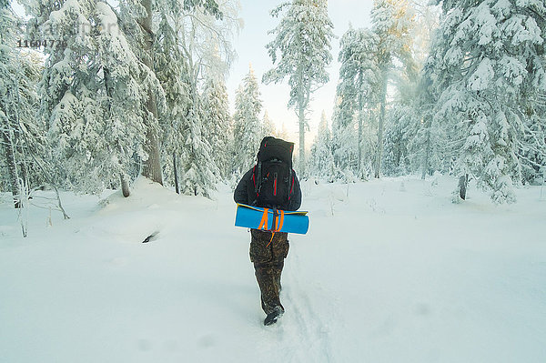 Kaukasischer Mann beim Wandern im verschneiten Wald