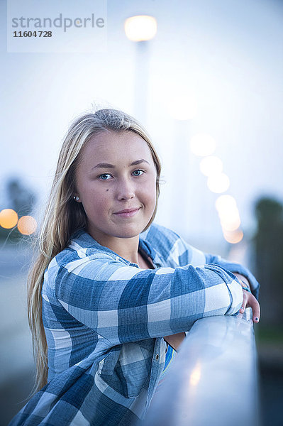 Porträt eines lächelnden kaukasischen Teenagers  der sich an ein Geländer lehnt