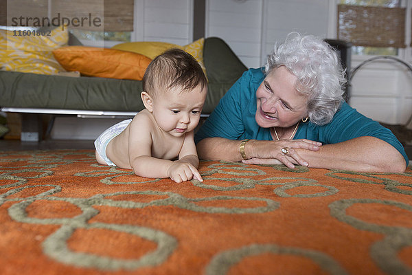 Großmutter und Enkel auf dem Teppich liegend