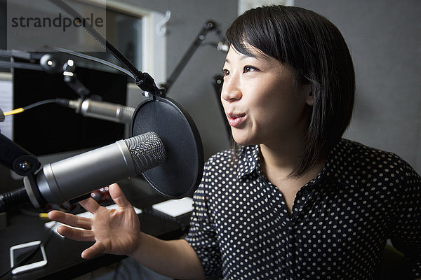 Asiatische Frau spricht ins Mikrofon