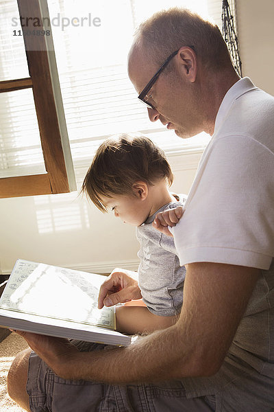 Vater liest seinem Sohn auf dem Schoß ein Buch vor