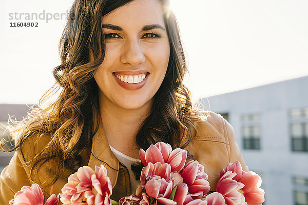 Porträt einer lächelnden gemischtrassigen Frau mit Blumen
