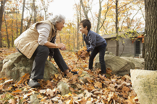 Großmutter und Enkel spielen mit Herbstblättern