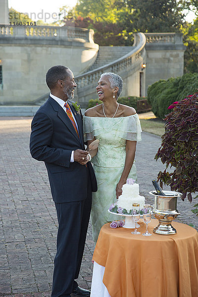 Schwarzes Paar lachend in der Nähe der Hochzeitstorte