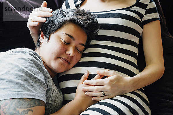 Schwangere lesbische Paar kuscheln auf Sofa