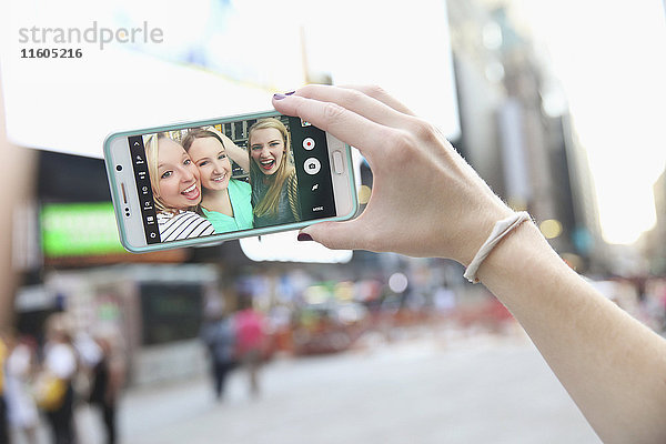 Arm einer kaukasischen Frau  die für ein Handy-Selfie mit Freunden posiert