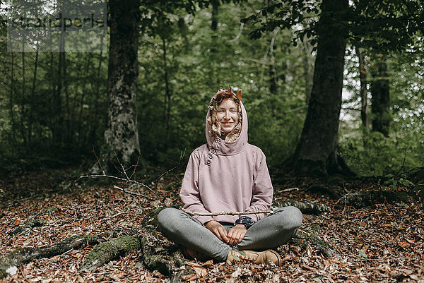 Kaukasische Frau sitzt mit Herbstblättern in der Kapuze