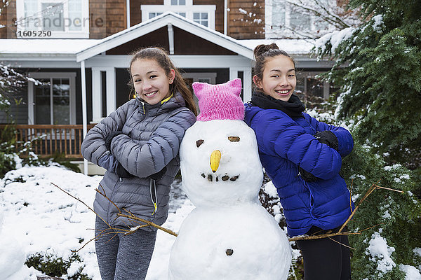 Mixed Race Mädchen posieren mit Schneemann trägt rosa Hut mit Ohren