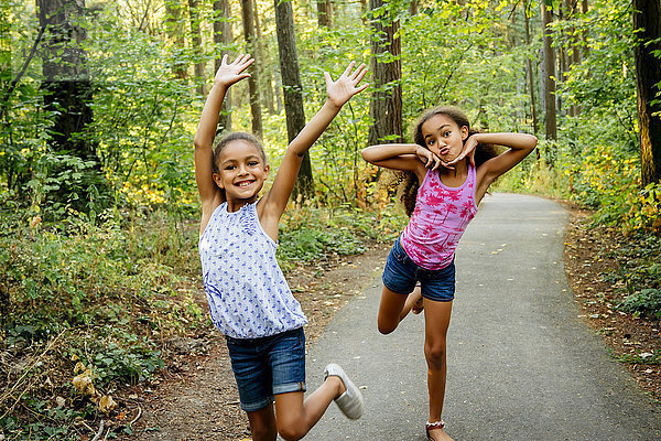 Mixed Race Schwestern mit Spaß posieren auf Waldweg