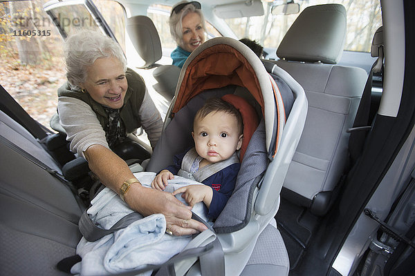 Großmutter befestigt Baby-Enkel im Autositz
