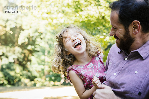 Kaukasischer Vater trägt lachend seine Tochter