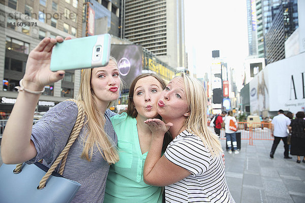 Puckering kaukasischen Frauen posieren für Handy-Selfie in der Stadt