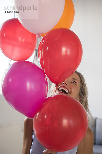 Lächelnde kaukasische Frau hält mehrfarbige Heliumballons
