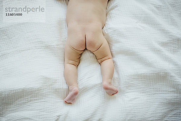 Nacktes Gesäß von Mixed Race Baby Mädchen auf der Decke liegend