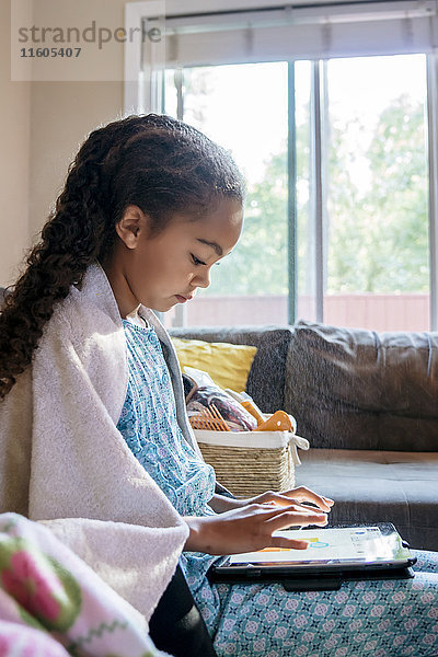 Mixed-Race-Mädchen mit digitalem Tablet auf dem Sofa