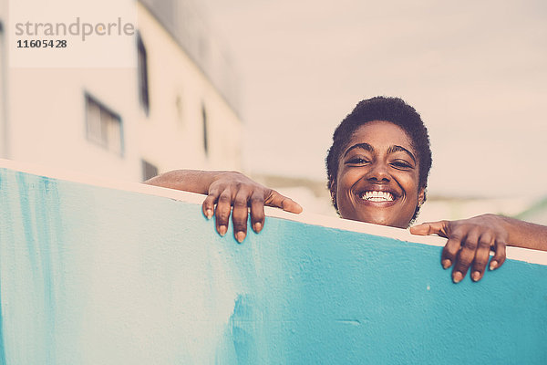 Lächelnde afroamerikanische Frau  die über die blaue Wand blickt