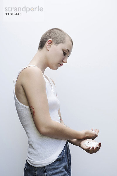 Ernste kaukasische Frau mit rasiertem Kopf hält Pillen