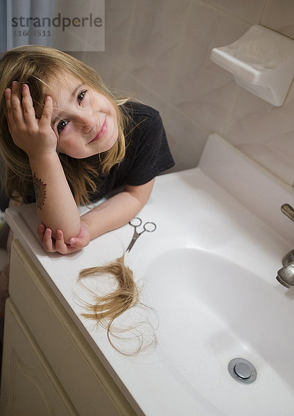 Kaukasisches Mädchen schneidet sich im Badezimmer die Haare