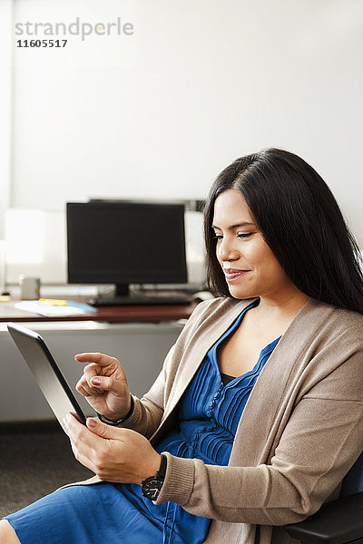 Eine Frau aus dem pazifischen Raum benutzt ein digitales Tablet im Büro