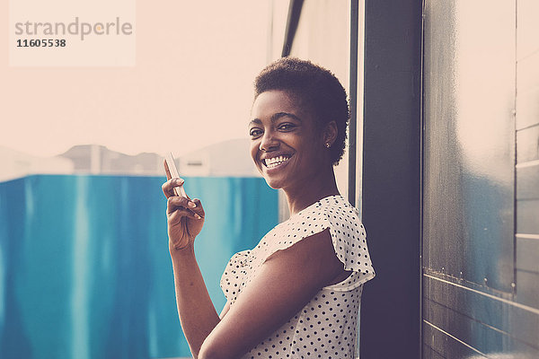 Lächelnde afroamerikanische Frau mit Mobiltelefon in der Hand