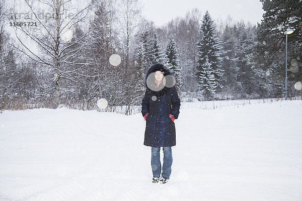Ganzkörperporträt einer erwachsenen Frau  die auf einem schneebedeckten Feld steht.