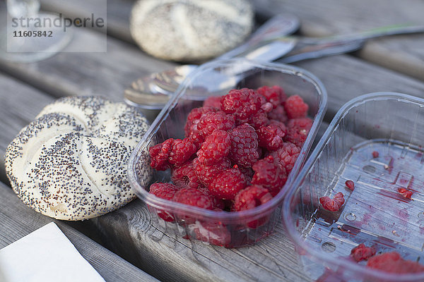 Himbeeren im Container mit Brötchen auf dem Tisch