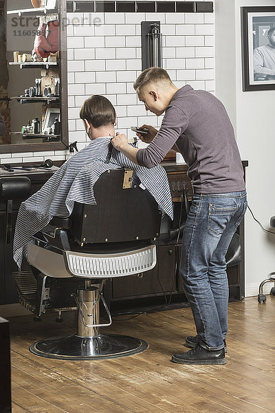 Friseur schneiden männlichen Kunden die Haare im Salon