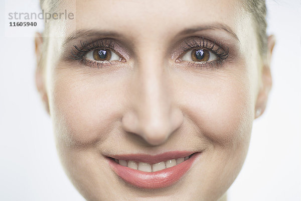 Nahaufnahme Porträt einer lächelnden erwachsenen Frau vor weißem Hintergrund