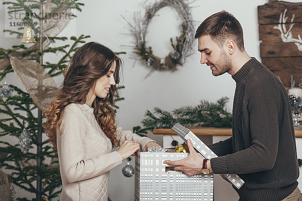 Seitenansicht des lächelnden Paares beim Verpacken von Weihnachtsgeschenken zu Hause