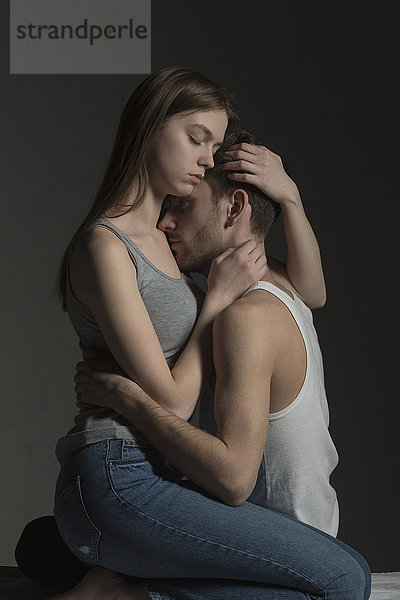 Romantisches junges Paar umarmt vor grauem Hintergrund