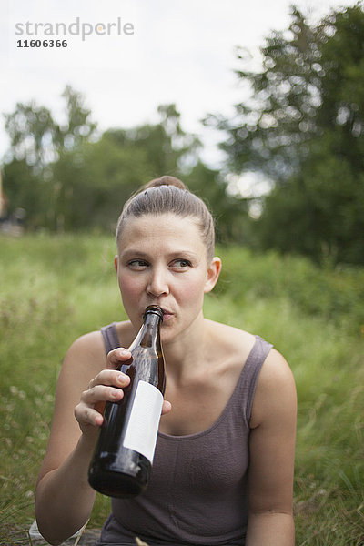 Mittlere erwachsene Frau schaut weg  während sie auf dem Feld Wein trinkt.