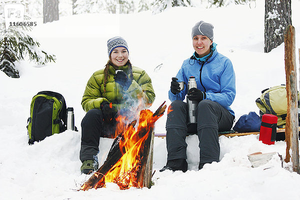 Frauen ruhen sich am Kamin im Winterwald aus