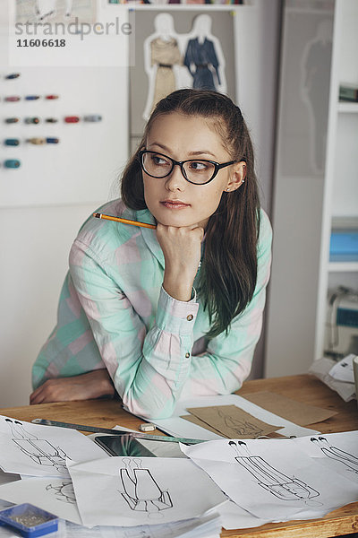 Nachdenklich schöne Modedesignerin mit Blick auf die Werkbank im Atelier