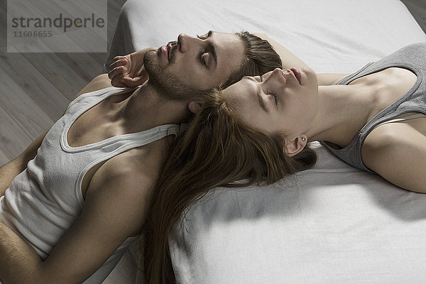 Hochwinkelansicht des Paares mit geschlossenen Augen  die sich auf dem Bett entspannen