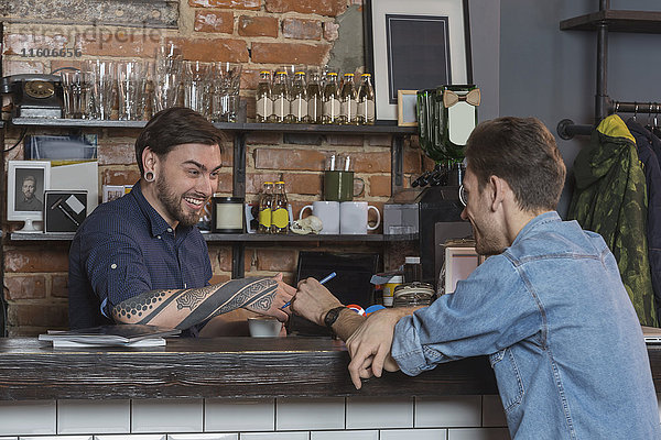 Fröhliche männliche Friseure sitzen an der Theke im Friseursalon