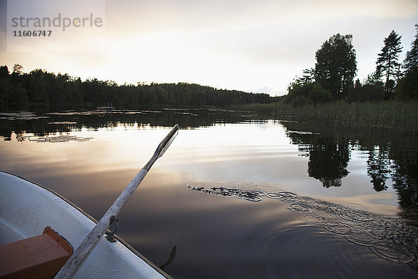 Abgeschnittenes Bild eines Ruderbootes  das bei Sonnenuntergang auf dem See festgemacht hat
