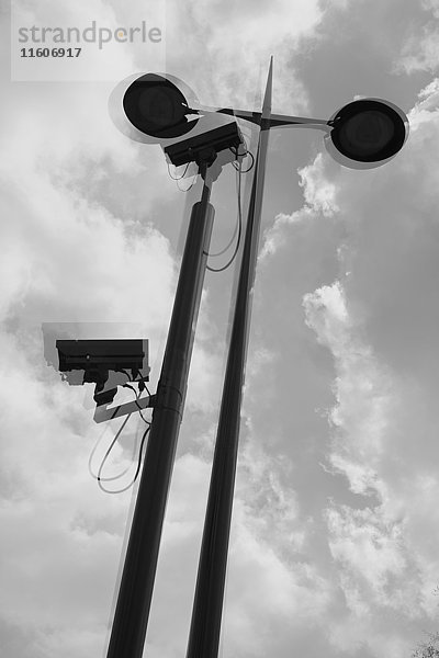 Mehrschichtiges Bild von Überwachungskameras und Straßenleuchten gegen bewölkten Himmel