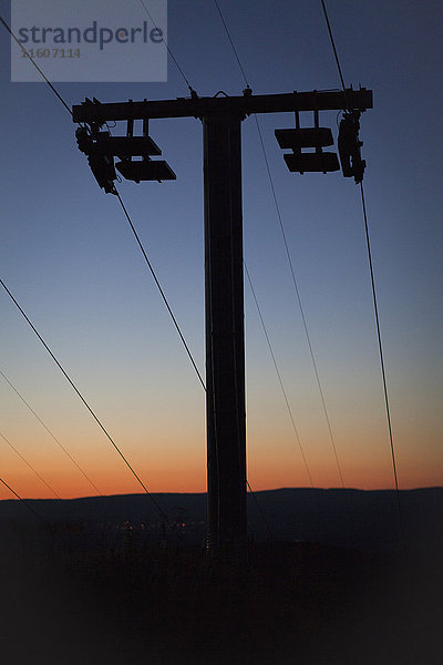 Niedriger Winkel der Silhouette des Strommastes auf dem Feld gegen den Himmel bei Sonnenuntergang