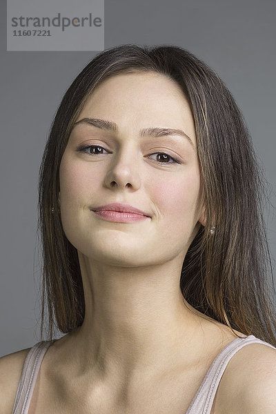 Porträt der schönen jungen Frau vor grauem Hintergrund