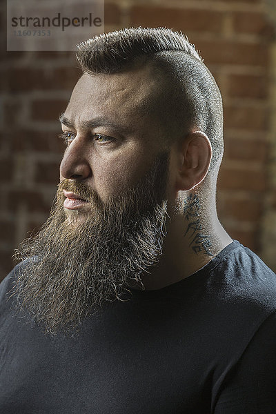 Nahaufnahme eines männlichen Friseurs mit Bart und Tattoo im Friseursalon