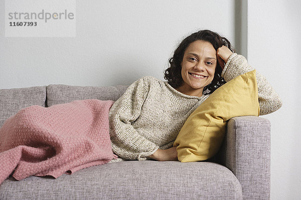 Porträt einer glücklichen Frau auf dem Sofa zu Hause