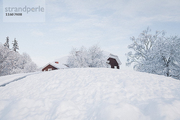 Flachwinkelansicht von Häusern auf schneebedecktem Hügel gegen den Himmel