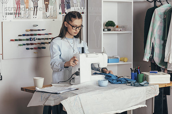 Modedesignerin mit Nähmaschine im Designstudio