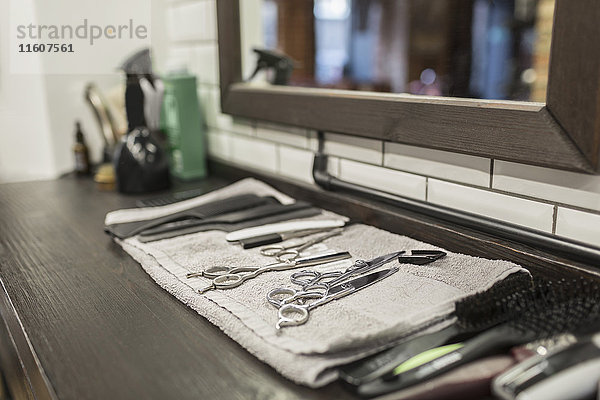 Nahaufnahme verschiedener Scheren und Kämme auf Serviette im Friseursalon