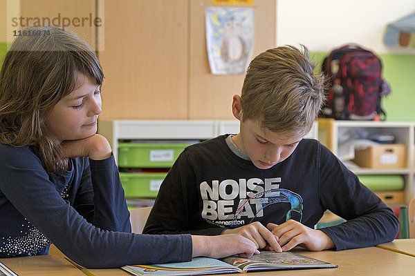 Schüler  Kinder lesen gemeinsam ein Buch  Klassenzimmer  Grundschule  Niedersachsen  Deutschland  Europa