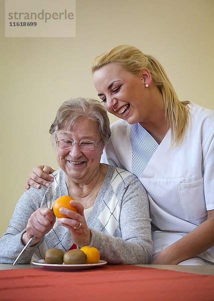 Krankenschwester hilft einer Seniorin beim Obstschälen  Deutschland  Europa