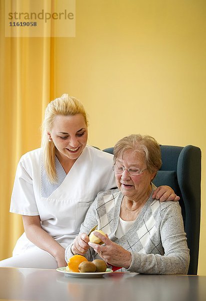 Krankenschwester hilft einer Seniorin beim Obstschälen  Deutschland  Europa